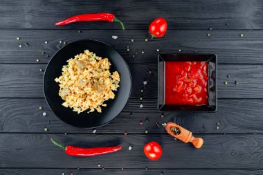 Geleneksel Asya yemeği - pirinç pilavı, sebze ve et siyah arka planda bir tabakta. Asya yemekleri. Yukarıdan görüntüle.