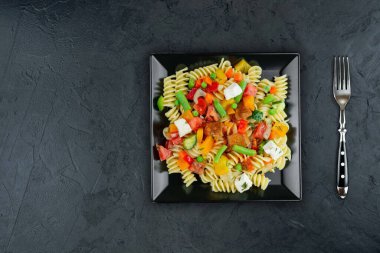 Sebzeli makarna, kuşkonmaz, bezelye, dolmalık biber, domates, sos, siyah arkaplanda mozzarella peyniri. Sebzeli İtalyan makarnası ve koyu bir arka planda baharat. Anlaşıldı..