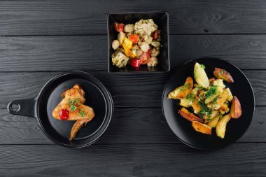 Mantarlı kızarmış patates ve baharatlı siyah arka planda domates. Sebzeli patates ve siyah tavuklu baharat..