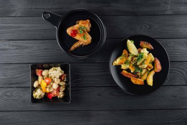 Mantarlı kızarmış patates ve baharatlı siyah arka planda domates. Sebzeli patates ve siyah tavuklu baharat..