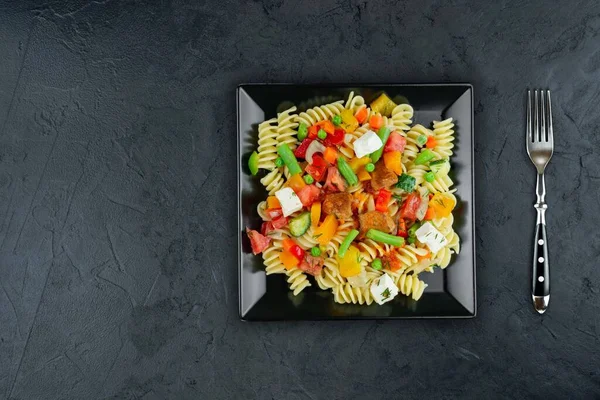 Sebzeli makarna, kuşkonmaz, bezelye, dolmalık biber, domates, sos, siyah arkaplanda mozzarella peyniri. Sebzeli İtalyan makarnası ve koyu bir arka planda baharat. Anlaşıldı..