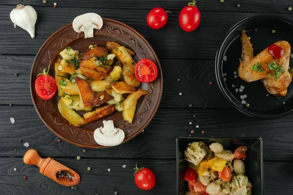 Mantarlı kızarmış patates ve baharatlı siyah arka planda domates. Sebzeli patates ve siyah tavuklu baharat..