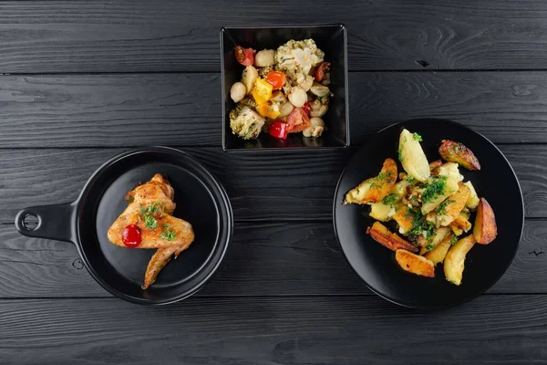 Mantarlı kızarmış patates ve baharatlı siyah arka planda domates. Sebzeli patates ve siyah tavuklu baharat..