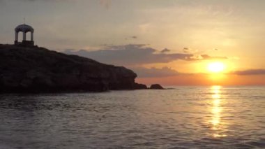 Deniz kıyısında, kayaların ve çardakların yanında güzel bir gün batımı. Deniz kıyısındaki güzel çardak.