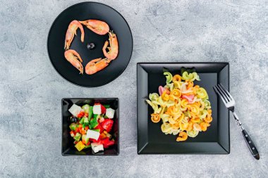 Gri arkaplanda karidesli çok renkli makarna..