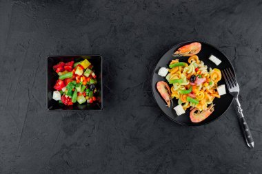 Siyah beton arka planda karidesli çok renkli makarna. Siyah tabakta İtalyan makarnası servis ediyorum..