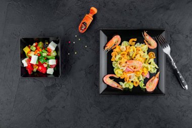 Siyah beton arka planda karidesli çok renkli makarna. Siyah tabakta İtalyan makarnası servis ediyorum..