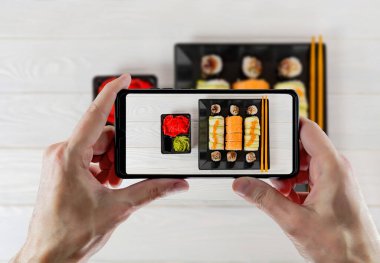 Beyaz dokuma tahtasında lezzetli suşi. Suşi, beyaz ahşap arka planda siyah bir tabağa kurulmuş..