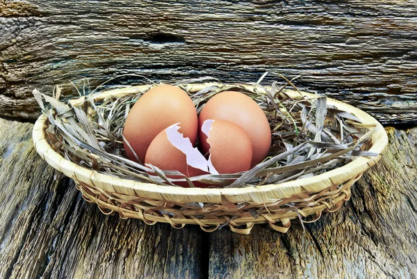 Eggs cracked egg,placed in a basket on the wooden background — Stock Photo, Image