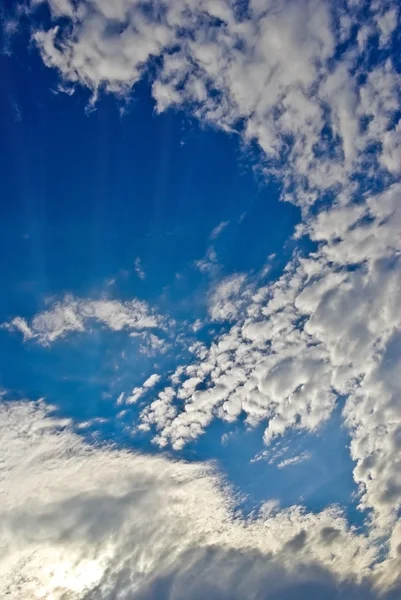 Luz del sol entre las nubes en el cielo azul — Foto de Stock