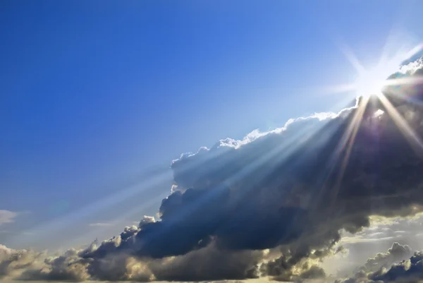 Luz del sol entre las nubes en el cielo azul — Foto de Stock