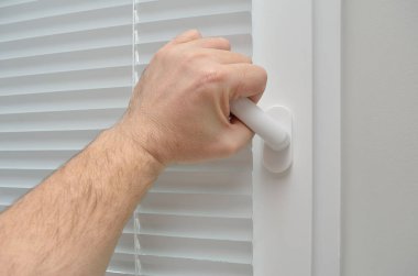 Adamın eli beyaz, plastik bir pencere açar.