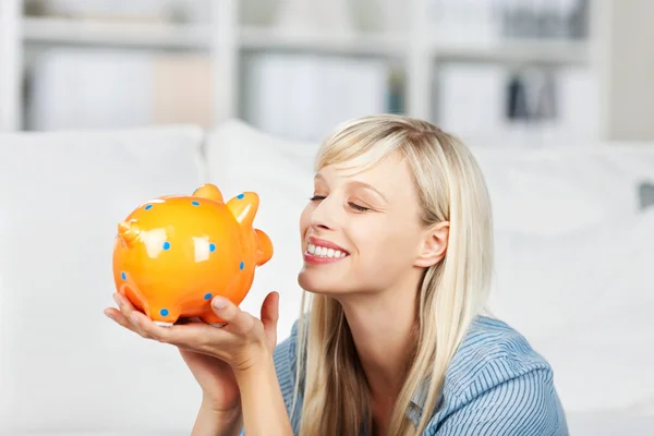 Smiling woman looking at her piggy bank — Stock Photo, Image