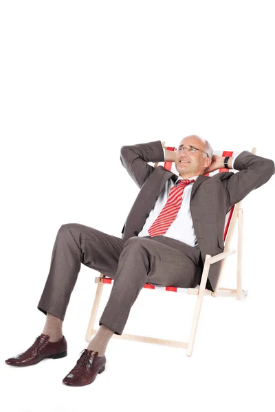 Empresario con las manos detrás de la cabeza relajante en la silla de cubierta — Foto de Stock