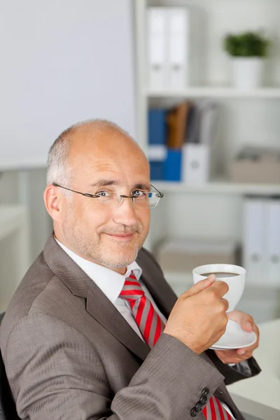 Businessman smiling and having a cup of coffee — Stock Photo, Image