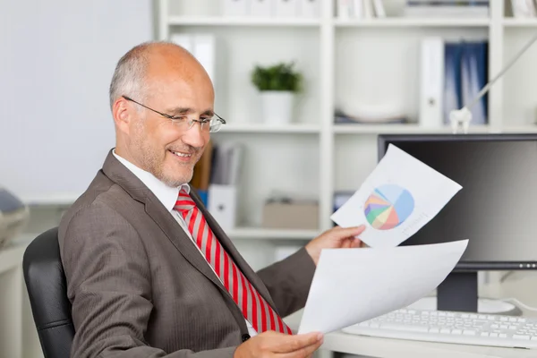 Бизнесмен анализирует документы на рабочем столе — стоковое фото
