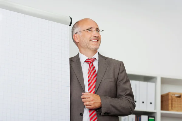 Smiling businessman presenting at flipchart — Stock Photo, Image