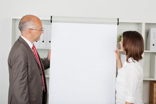 Collega's op zoek op witte flipchart — Stockfoto