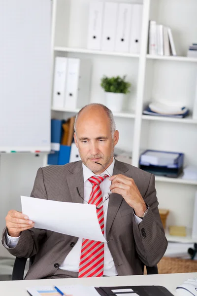 Businessman Looking At Document At Desk — Stock Photo, Image