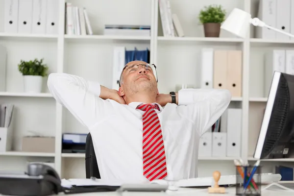 Geschäftsmann mit Händen hinter dem Kopf am Schreibtisch — Stockfoto