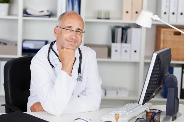 Улыбающийся доктор с подбородком на руке — стоковое фото