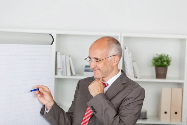 Homme d'affaires confiant pointant sur le tableau à feuilles mobiles — Photo