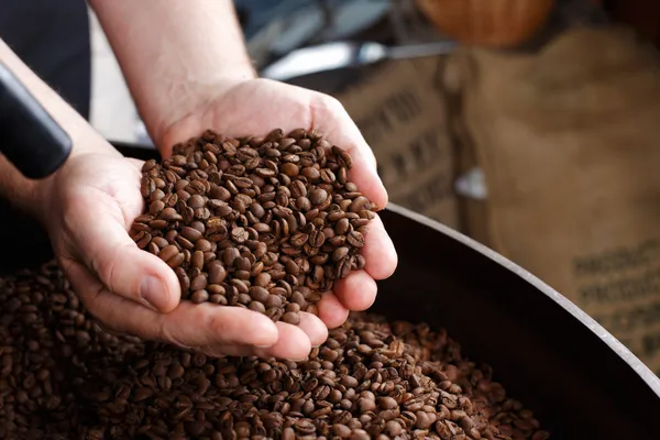 Hand removing roasted coffee beans — Stock Photo, Image