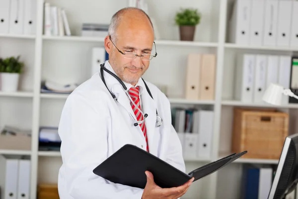 Cartella di lettura medico contro gli scaffali in ufficio — Foto Stock