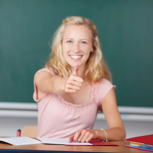 Lehrerin zeigt Daumen-hoch-Schild am Schreibtisch — Stockfoto