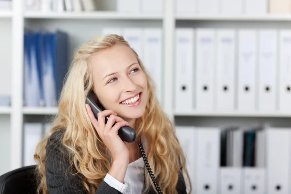 Счастливая женщина в офисе разговаривает по телефону — стоковое фото