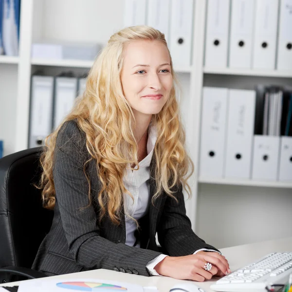 Mujer de negocios sonriendo mientras mira hacia el escritorio — Foto de Stock