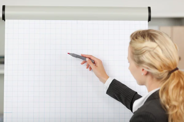 Blond zakenvrouw schrijven op het flip-overbord noteren in office — Stockfoto