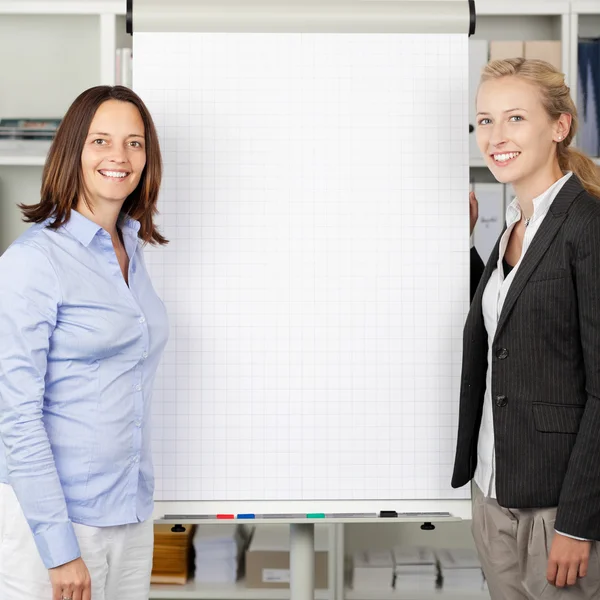 Mujeres de negocios de pie cerca del rotafolio — Foto de Stock