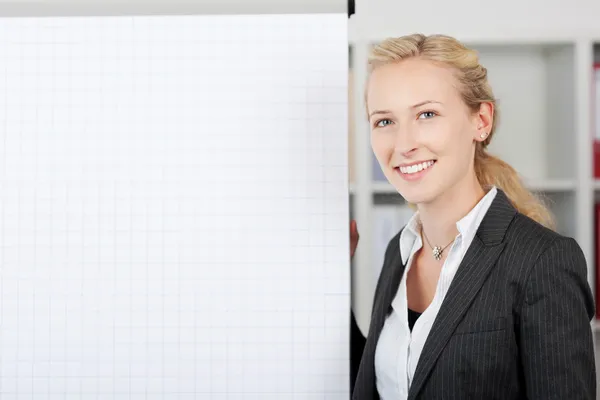 Femme d'affaires souriante debout près tableau à feuilles mobiles au bureau — Photo