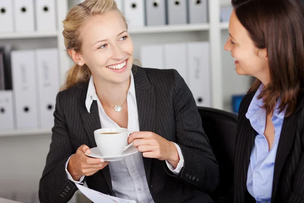 Affärskvinna med kopp kaffe medan du tittar på medarbetare — Stockfoto