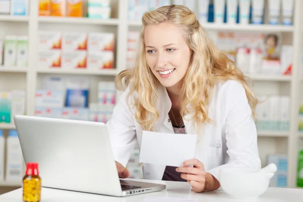 Pharmacist Holding Prescription While Using Laptop At Coun — Stock Photo, Image