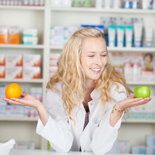 Apotheker vergelijken van apple en oranje — Stockfoto