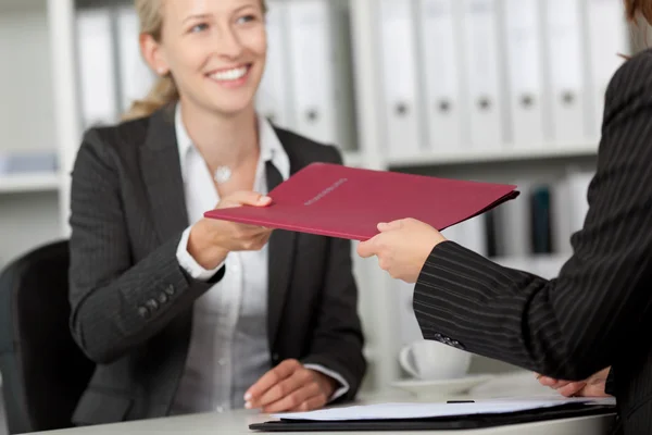 Businesswoman Receiving File From Coworker At Desk — Stock Photo, Image