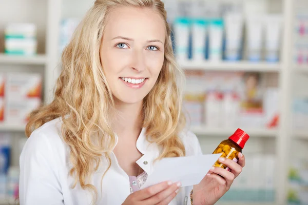 Farmacista femminile in possesso di carta e bottiglia di prescrizione — Foto Stock