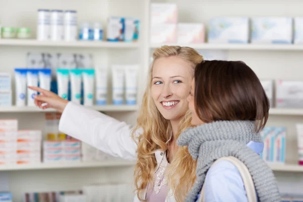 Vrouwelijke apotheker wijzend op geneesmiddelen terwijl kijken naar custome — Stockfoto