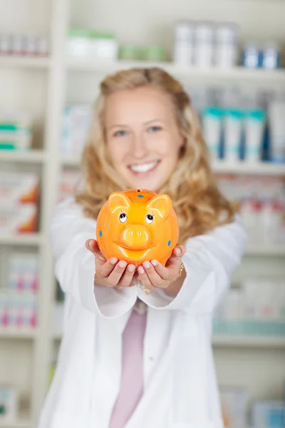 Kobieta farmaceuta gospodarstwa piggy bank — Zdjęcie stockowe