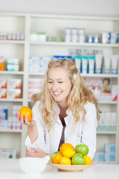 Pharmacist Holding Orange At Pharmacy Counter — Stock Photo, Image
