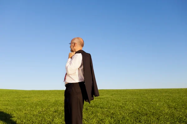 Zijaanzicht van volwassen zakenman permanent op gras veld — Stockfoto