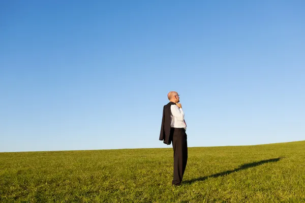 Зрілі бізнесмен, стоячи на травою поле — стокове фото