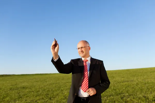 Businessman Writing On Invisible Screen With Marker On Field — Stock Photo, Image