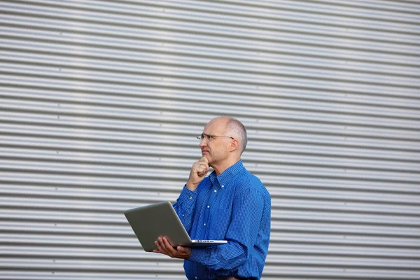 Empresário atencioso com laptop enquanto olha para longe — Fotografia de Stock