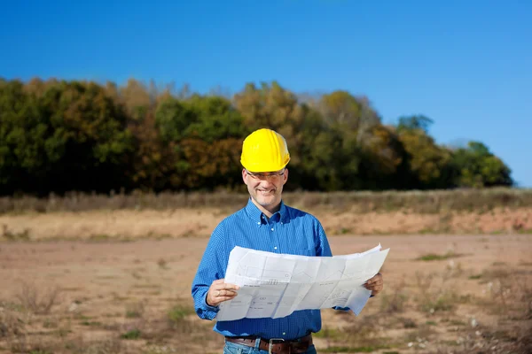 Architecte masculin tenant le plan directeur sur le chantier de construction — Photo