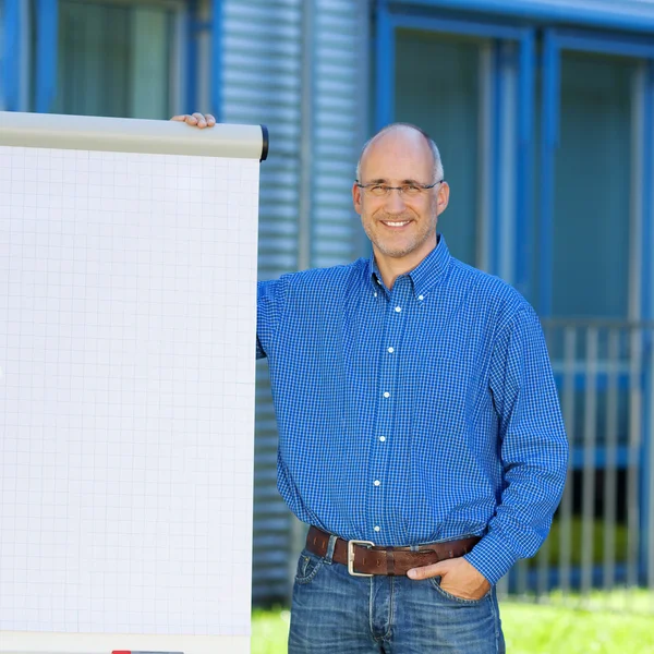 Businessman With Hand In Pocket Standing By Flipchart — Stock Photo, Image