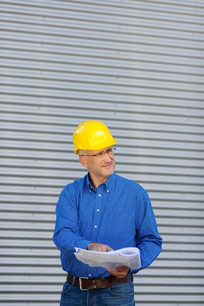 Architect bedrijf blauwdruk terwijl kijken weg — Stockfoto