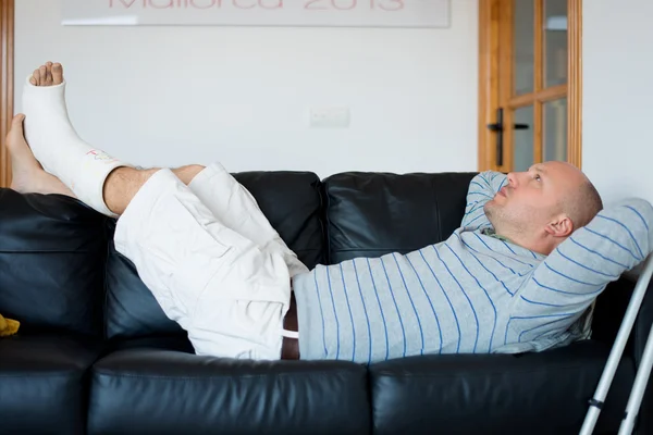 Sérült férfi feküdt a kanapén — Stock Fotó